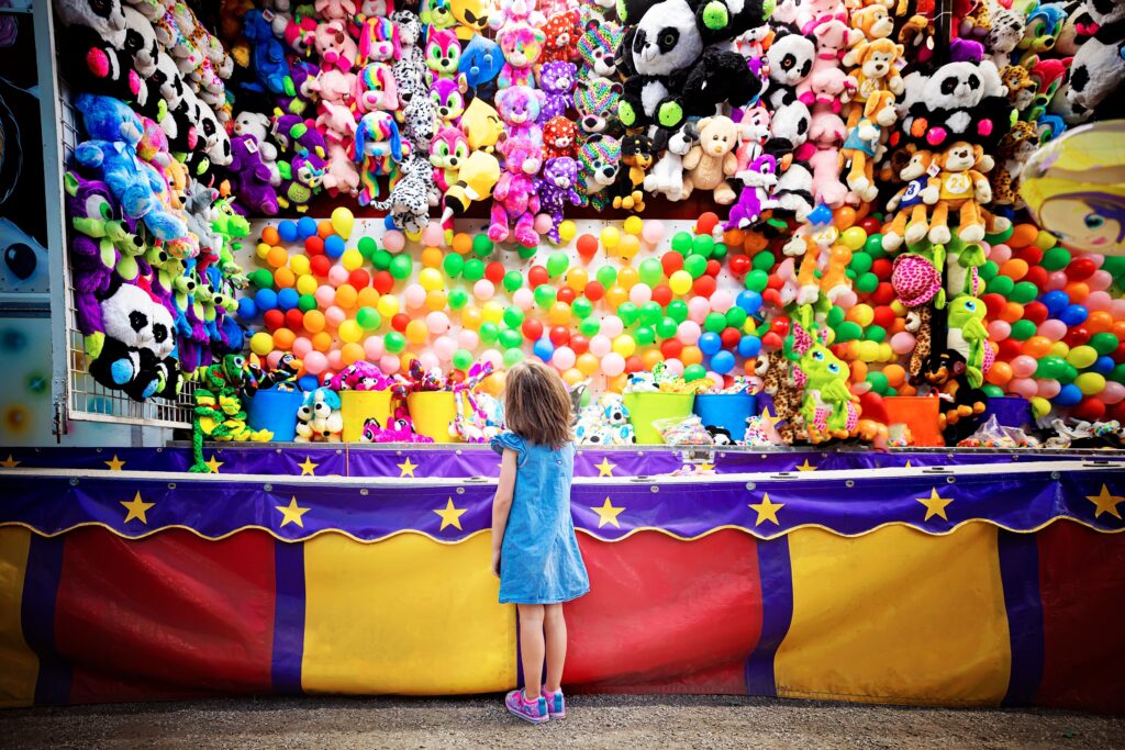 Girl at balloon dart game booth at county fair