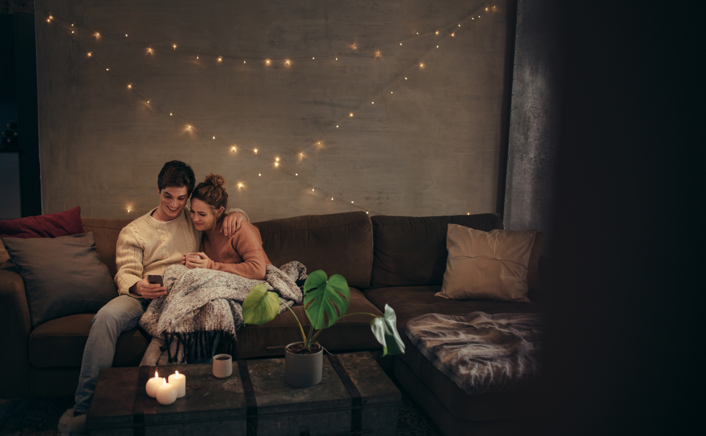 Couple cuddle on couch in blanket