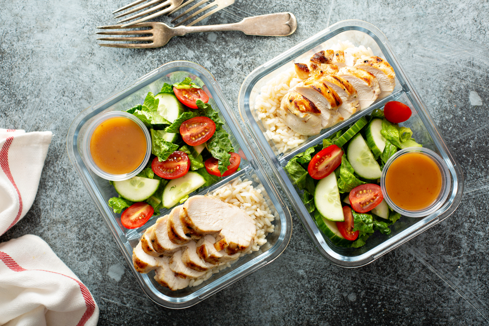 Meal prep lunch box containers with grilled chicken and fresh vegetables