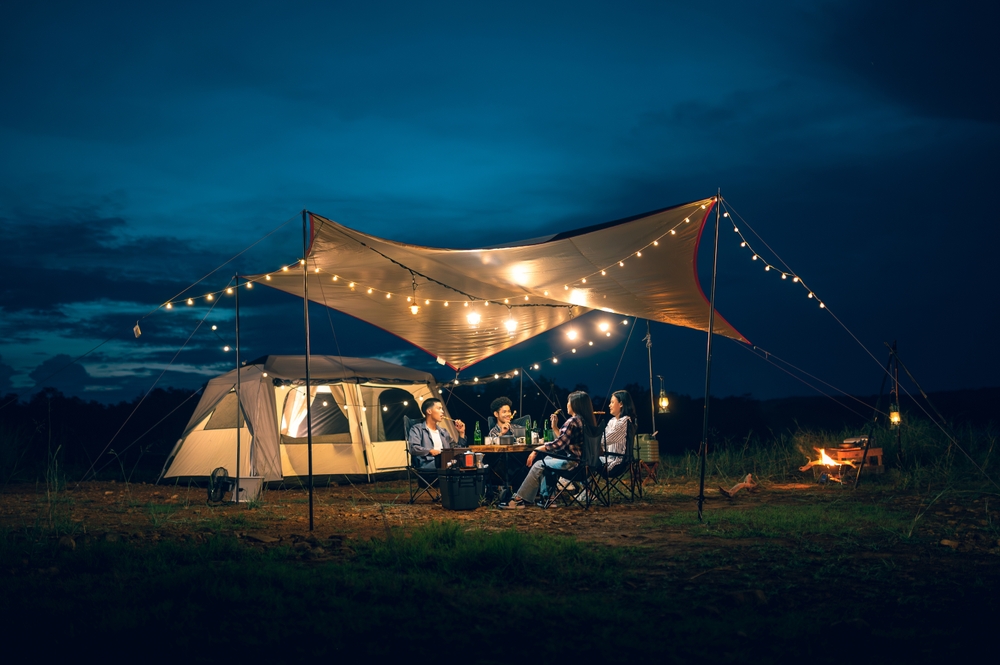 couple drinking and barbecue in a romantic camping setting. Groups of friends and couples having a drink party in a camping atmosphere amidst forests and rivers.