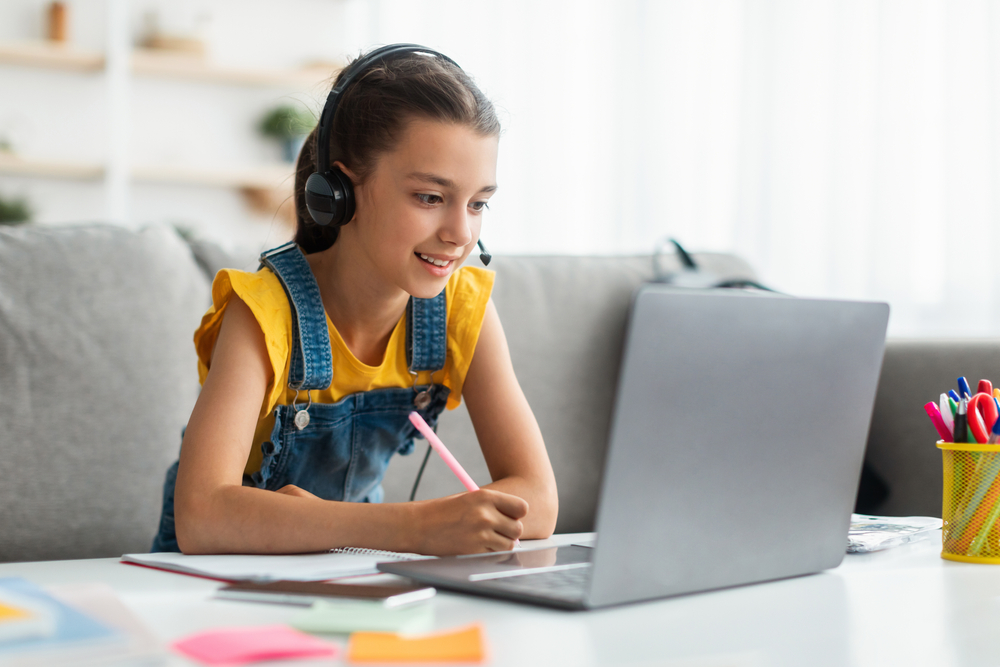 Little female student having video conference e-learning with teacher and classmates on computer in living room at home. Homeschooling and distance learning ,online education and internet concept